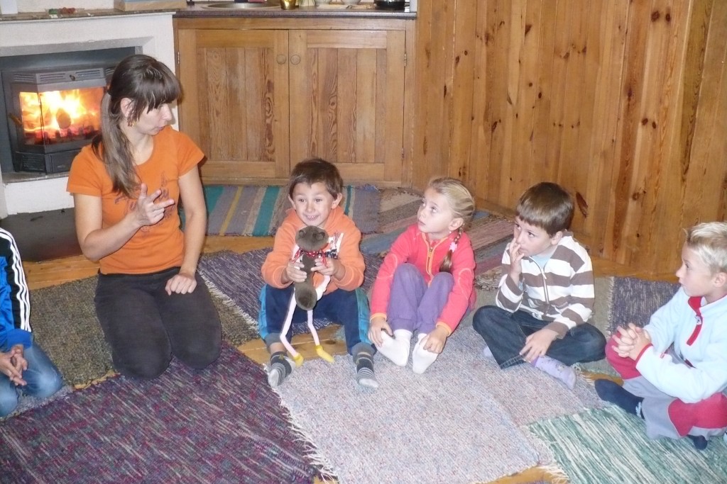 Děti sedí v kruhu a poslouchají.