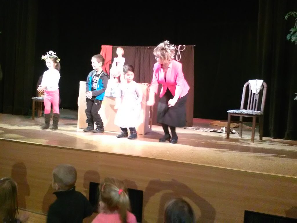 Děti hrají na pódiu s herečkou.