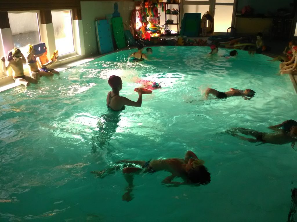Děti plavou v bazénu.