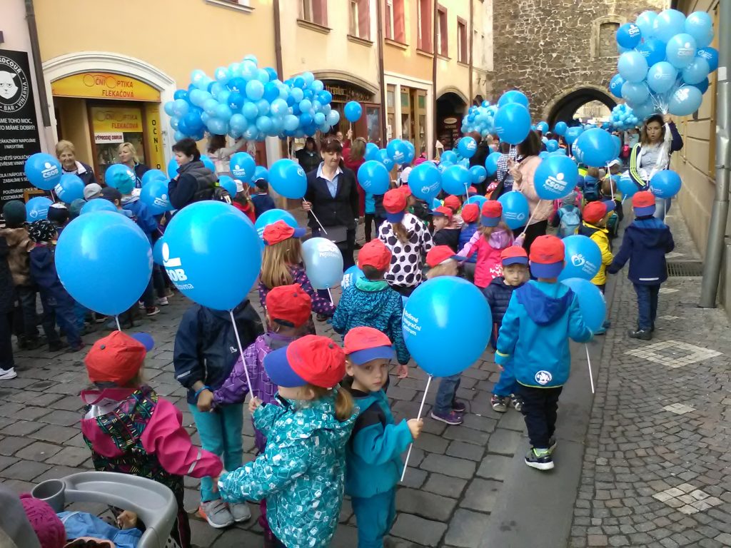 Děti jdou v průvodu s modrým balónkem.