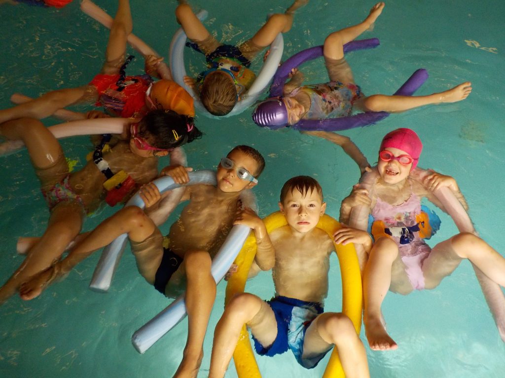 Děti plavou v bazénu na zádech.