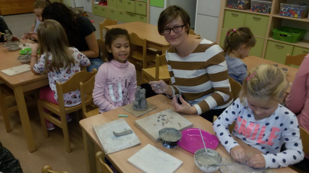 Děti s rodiči vyrábějí keramické výrobky.