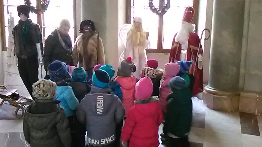 Děti si prohlížejí figuríny Mikuláše, anděla a čerta.