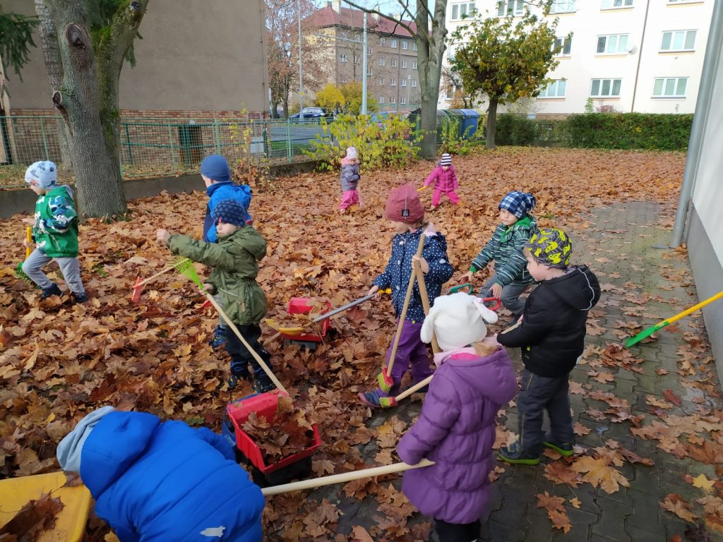 Děti hrabou listí.