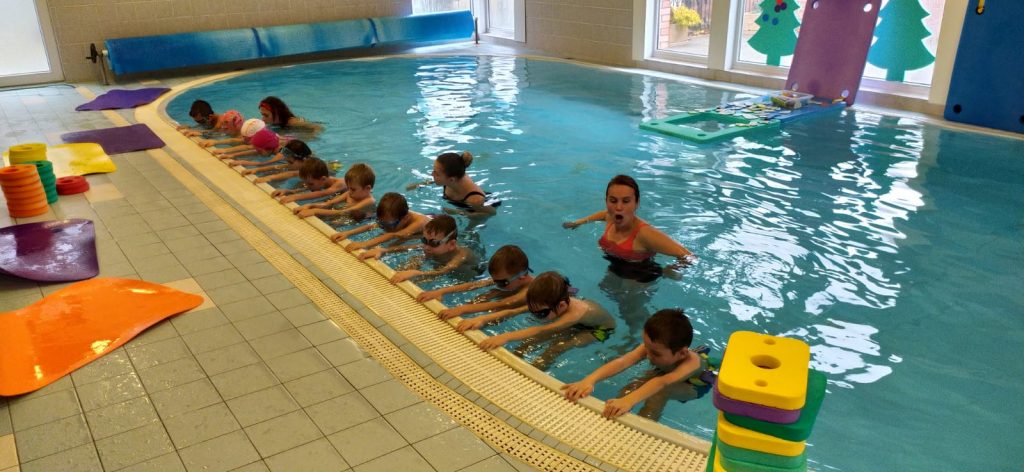 Děti se v bazénu učí plavat.