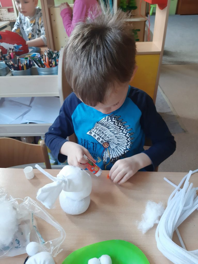 Chlapeček vyrábí sněhuláka Olafa.