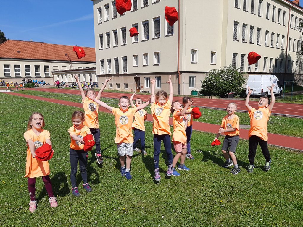 Děti vyhazují klobouky do vzduchu.