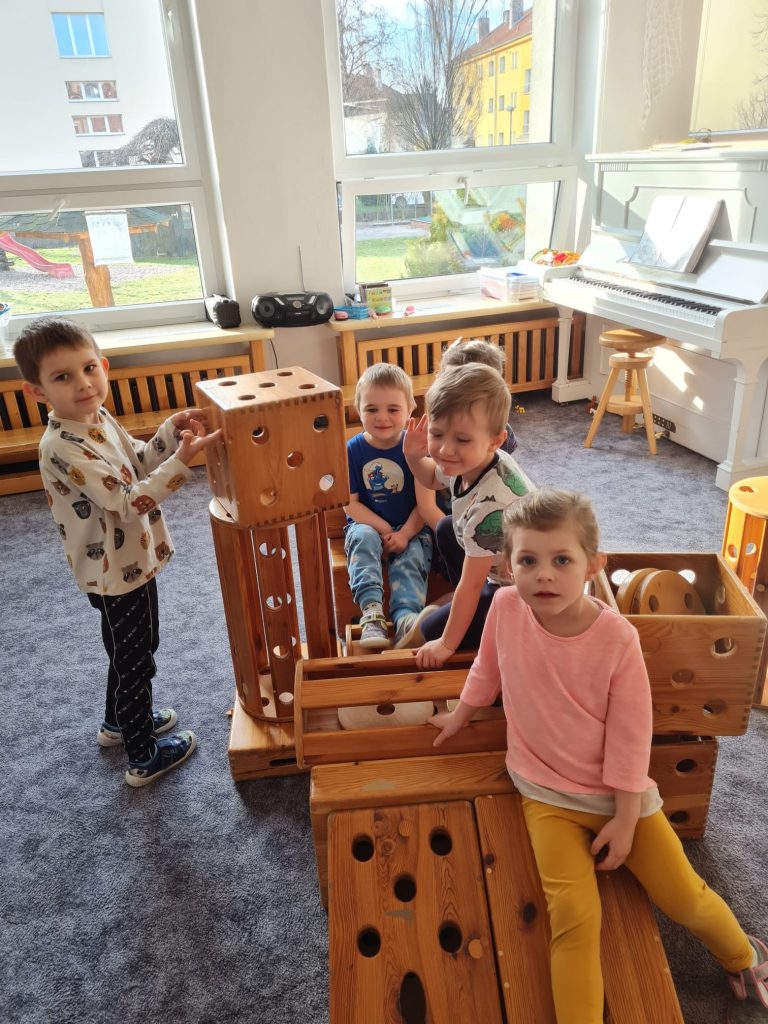 Děti staví z dřevěné stavebnice.