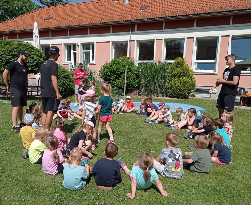 Děti a hokejisté na zahradě mateřské školy Kamínek.