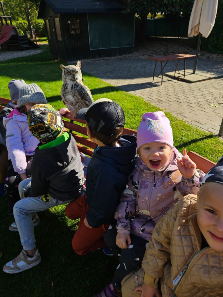 Dravec sedí na lavičce za dětmi.