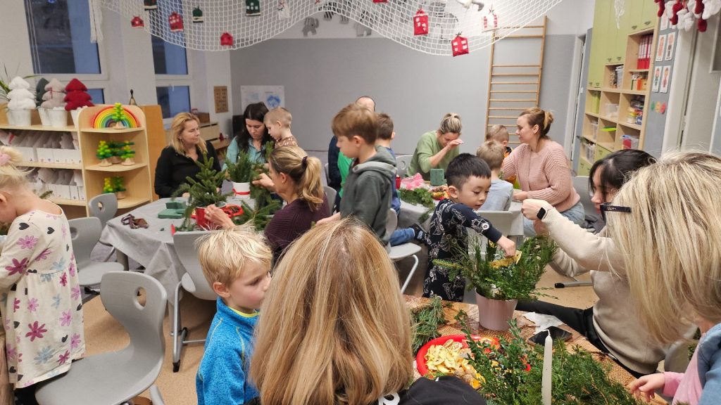 Rodiče s dětmi vyrábí vánoční svícínky.