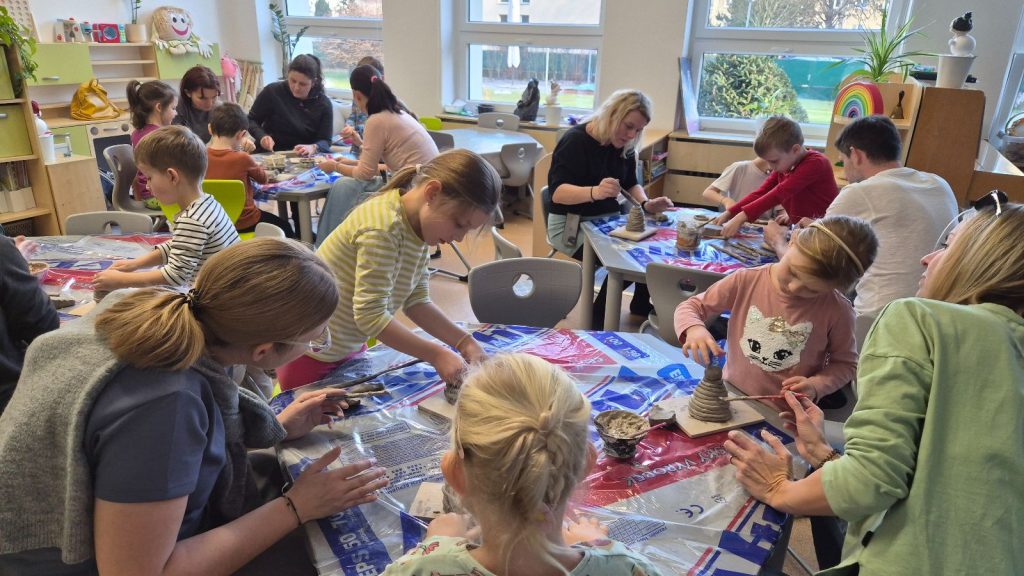 Děti tvoří s rodiči sněhuláka z keramické hlíny.